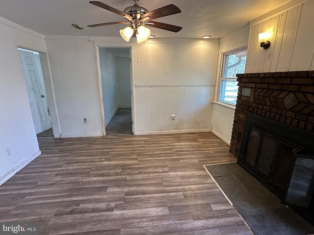 living area with a ceiling fan, a brick fireplace, wood finished floors, and wainscoting