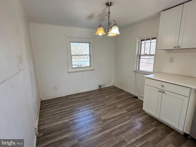 unfurnished dining area featuring dark wood finished floors, visible vents, a chandelier, and crown molding