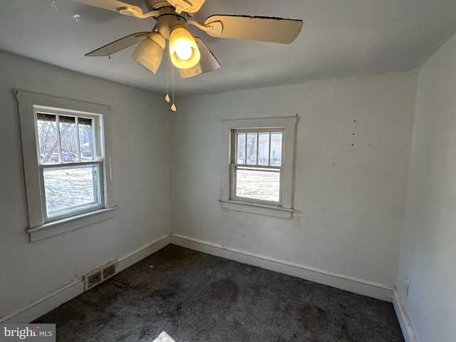 carpeted empty room with visible vents, a ceiling fan, and baseboards