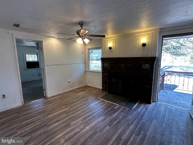 unfurnished living room with plenty of natural light, a textured ceiling, and dark wood-style flooring