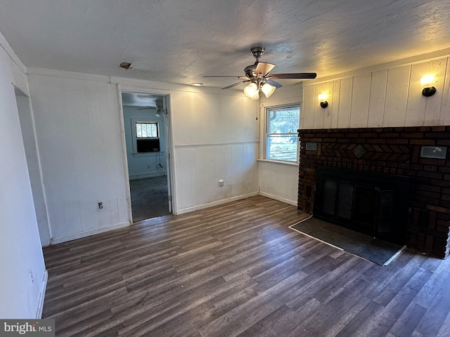 unfurnished living room with dark wood-type flooring, a brick fireplace, and a wealth of natural light