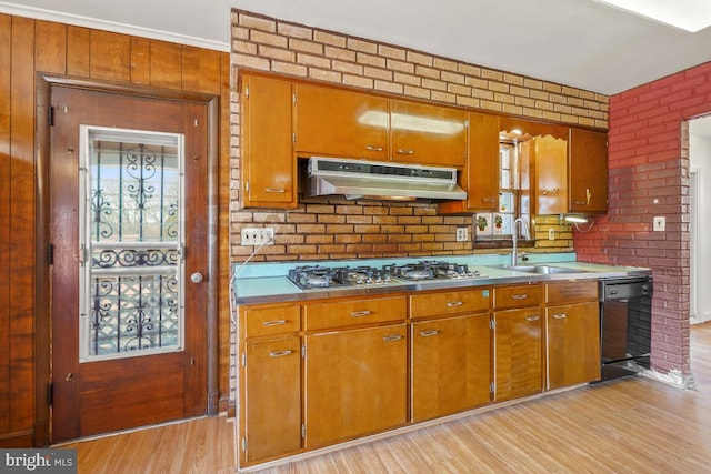 kitchen featuring under cabinet range hood, black dishwasher, brown cabinets, stainless steel gas stovetop, and a sink