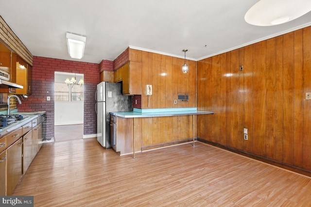 kitchen with light wood finished floors, light countertops, brown cabinets, freestanding refrigerator, and a sink