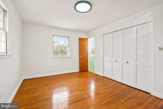 unfurnished bedroom with multiple windows, baseboards, and wood-type flooring