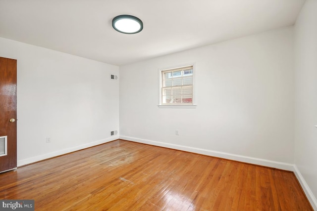 unfurnished room featuring light wood-type flooring, visible vents, and baseboards