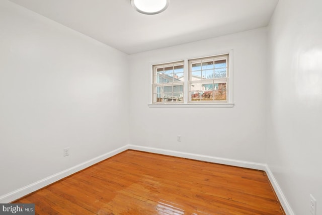 spare room with baseboards and wood finished floors