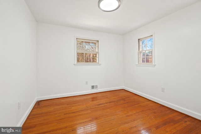 unfurnished room with hardwood / wood-style floors, baseboards, and visible vents