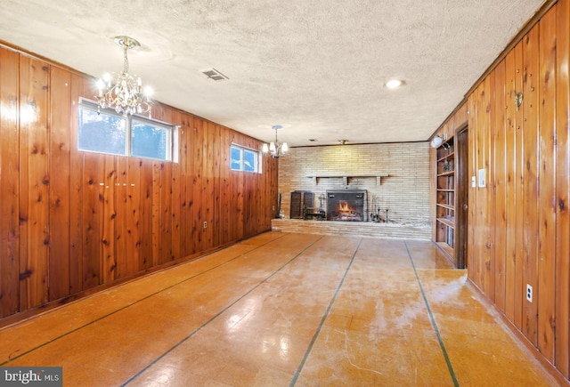 basement featuring a notable chandelier, visible vents, wood walls, and a textured ceiling