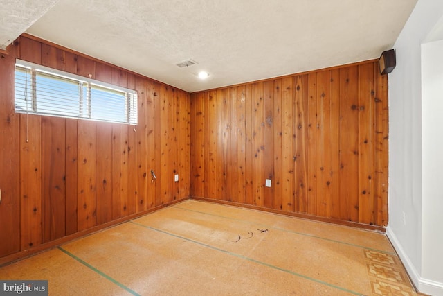 unfurnished room featuring wooden walls, visible vents, and baseboards