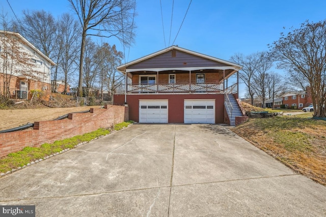 exterior space featuring an attached garage, covered porch, concrete driveway, and stairs