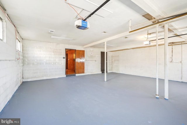 garage featuring concrete block wall and a garage door opener