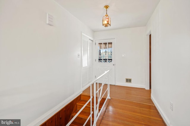 corridor with light wood-style floors, visible vents, and baseboards