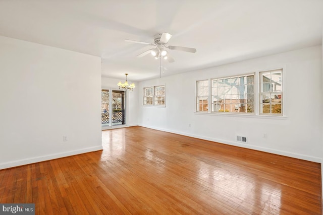 spare room featuring visible vents, ceiling fan with notable chandelier, baseboards, and hardwood / wood-style floors