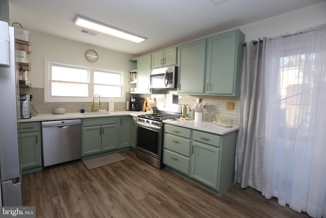 kitchen with visible vents, green cabinetry, open shelves, a sink, and appliances with stainless steel finishes