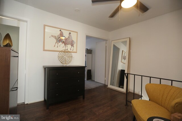 sitting room with dark wood-type flooring and a ceiling fan