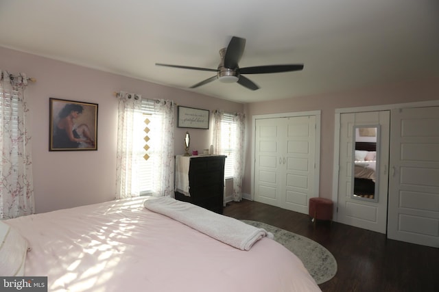 bedroom with dark wood-style floors, a ceiling fan, and multiple closets