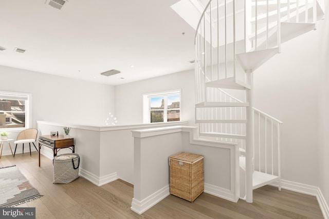 staircase featuring wood finished floors, visible vents, and baseboards