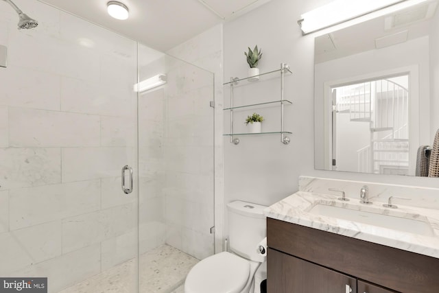 bathroom featuring a shower stall, toilet, and vanity