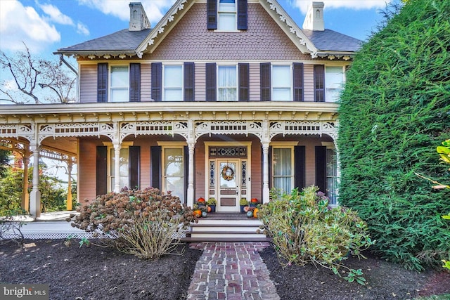 victorian house featuring covered porch and a chimney