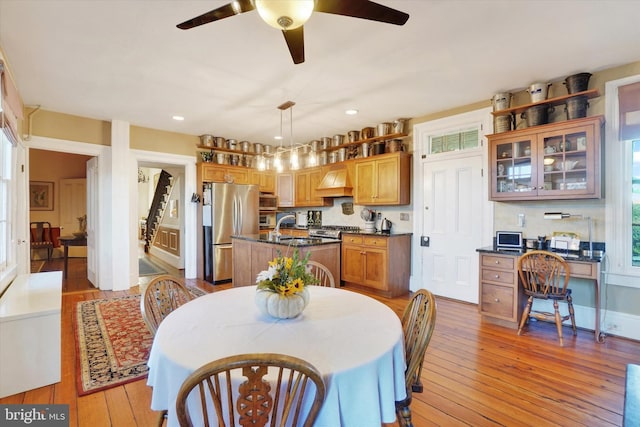 dining space with built in desk, ceiling fan, a healthy amount of sunlight, and light wood-style floors