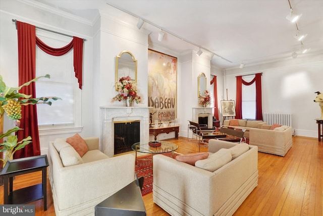 living room featuring track lighting, hardwood / wood-style floors, crown molding, and a premium fireplace