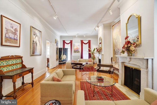 living room featuring a high end fireplace, ornamental molding, rail lighting, and wood finished floors