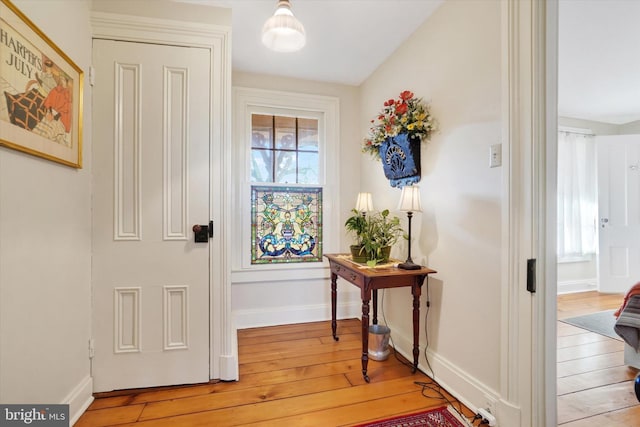 doorway to outside featuring baseboards and light wood finished floors