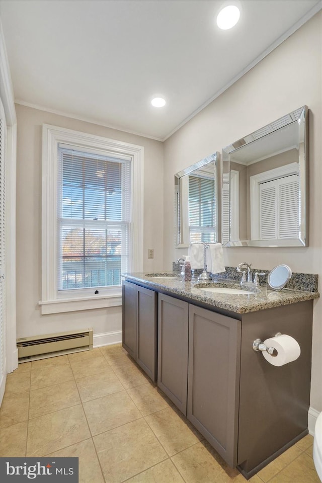 full bath featuring double vanity, a sink, tile patterned flooring, crown molding, and baseboard heating