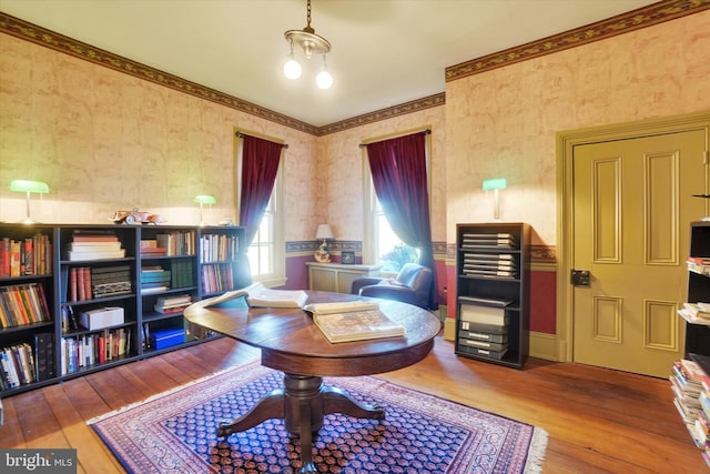 living area featuring wallpapered walls, hardwood / wood-style floors, and a chandelier