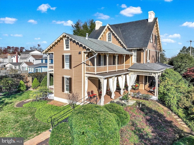 rear view of house featuring a patio area, a chimney, and a yard