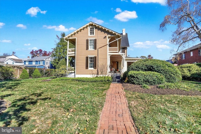 view of front of house featuring a front lawn and a balcony