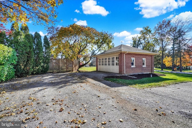 view of property exterior featuring brick siding, a lawn, and fence