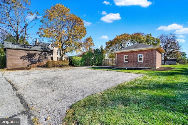 view of side of property with a yard, brick siding, and aphalt driveway