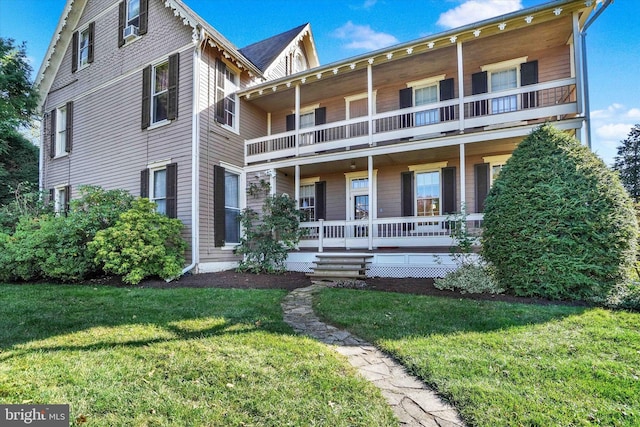 view of front of home with a balcony, covered porch, and a front yard