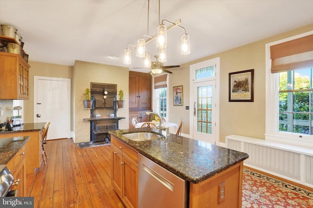 kitchen with a sink, plenty of natural light, radiator, brown cabinetry, and dishwasher