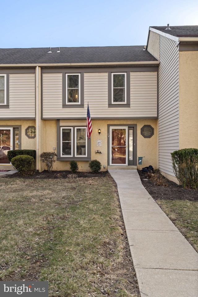 townhome / multi-family property featuring stucco siding and a front lawn