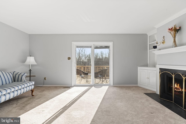 living area with a fireplace with flush hearth, built in features, baseboards, and carpet floors