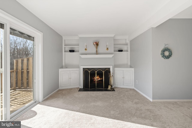 unfurnished living room with built in features, baseboards, a fireplace with flush hearth, and carpet floors