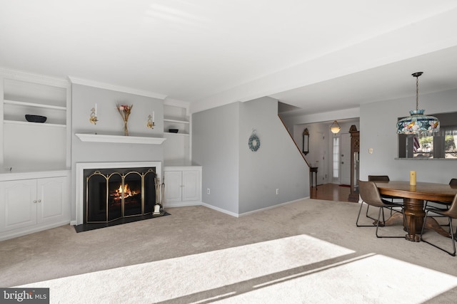 living area featuring a fireplace with flush hearth, baseboards, carpet floors, and built in features