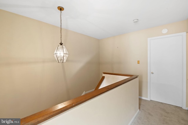 hallway featuring an upstairs landing, light colored carpet, and baseboards