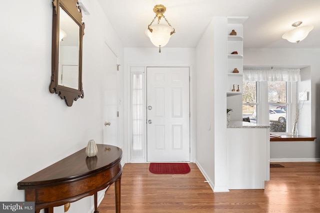 foyer featuring baseboards and wood finished floors