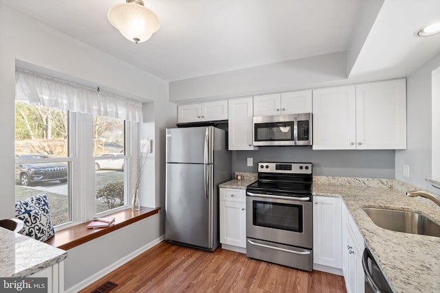 kitchen with a sink, stainless steel appliances, light wood-type flooring, and white cabinets