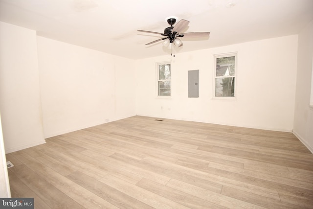 empty room with electric panel, ceiling fan, and light wood finished floors