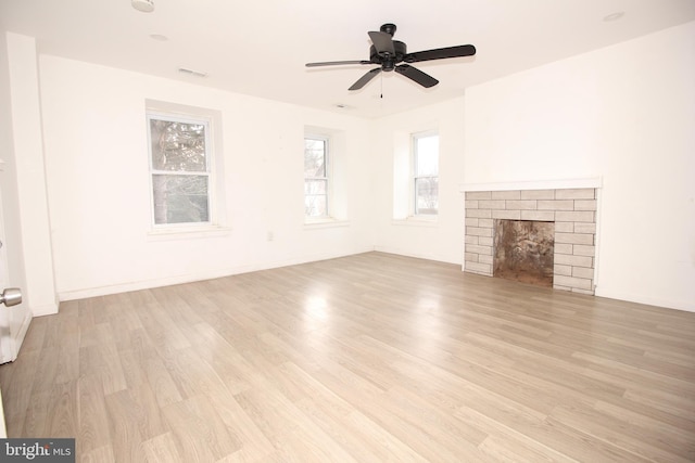 unfurnished living room featuring visible vents, a fireplace, light wood finished floors, baseboards, and ceiling fan