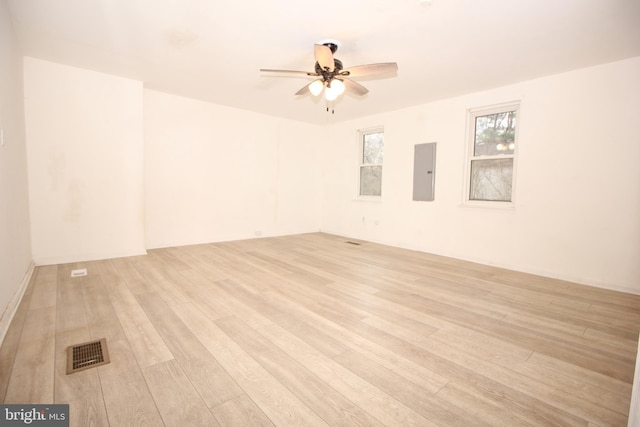 spare room featuring electric panel, a ceiling fan, visible vents, and light wood finished floors