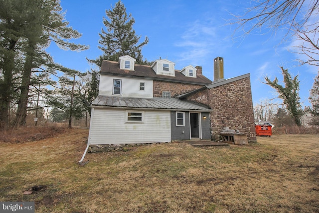 back of house with stone siding, metal roof, and a yard