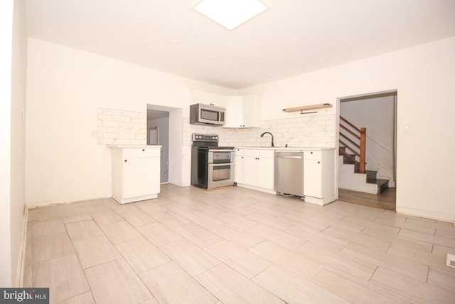 kitchen featuring a sink, decorative backsplash, light countertops, white cabinets, and stainless steel appliances