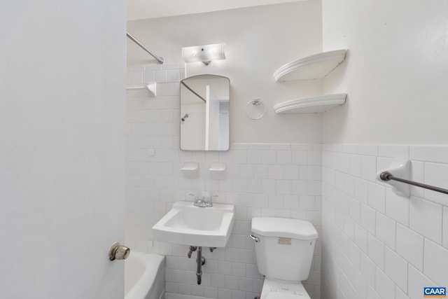 full bathroom featuring wainscoting, toilet, tile walls, and a sink