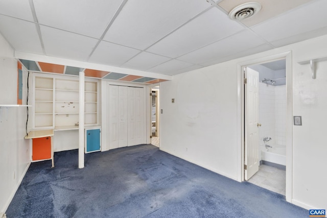 basement featuring visible vents, a paneled ceiling, and carpet