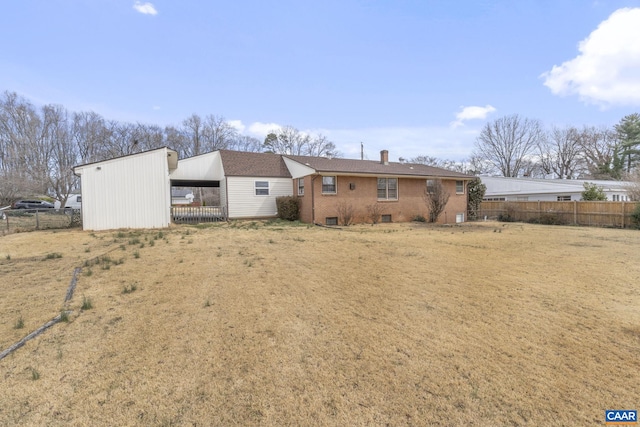 rear view of property featuring brick siding, an attached carport, a chimney, and fence